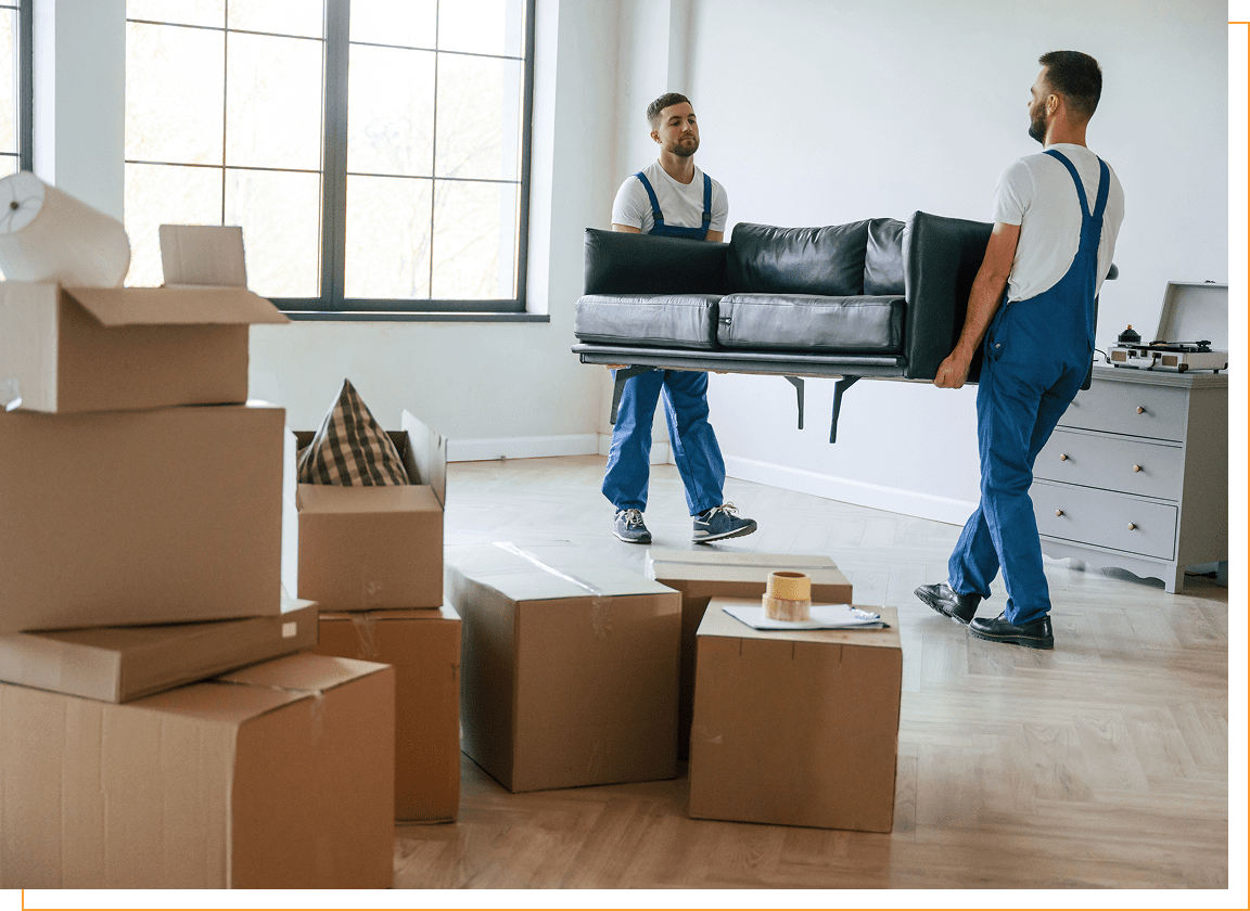 Movers carrying sofa in room with boxes.