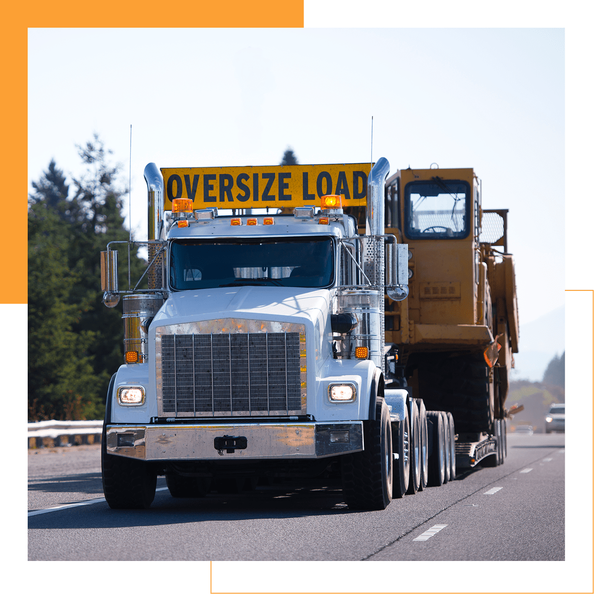 Truck carrying oversized construction equipment on highway.