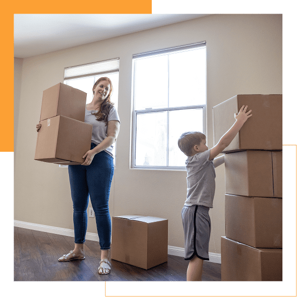 Woman and child carrying boxes in a bright empty room.